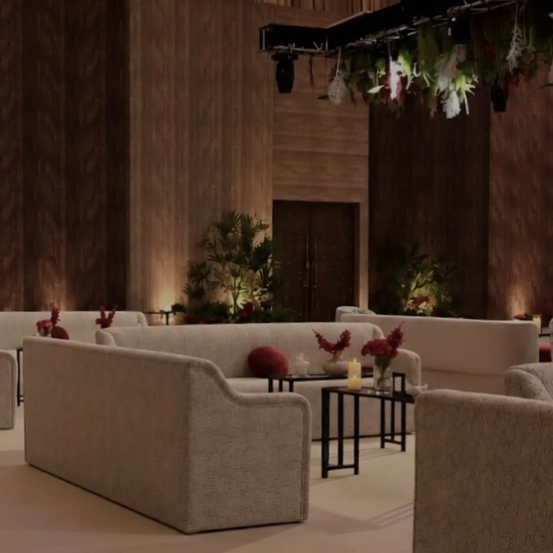 Ivory lounge sofas with red flowers and candles under suspended greenery